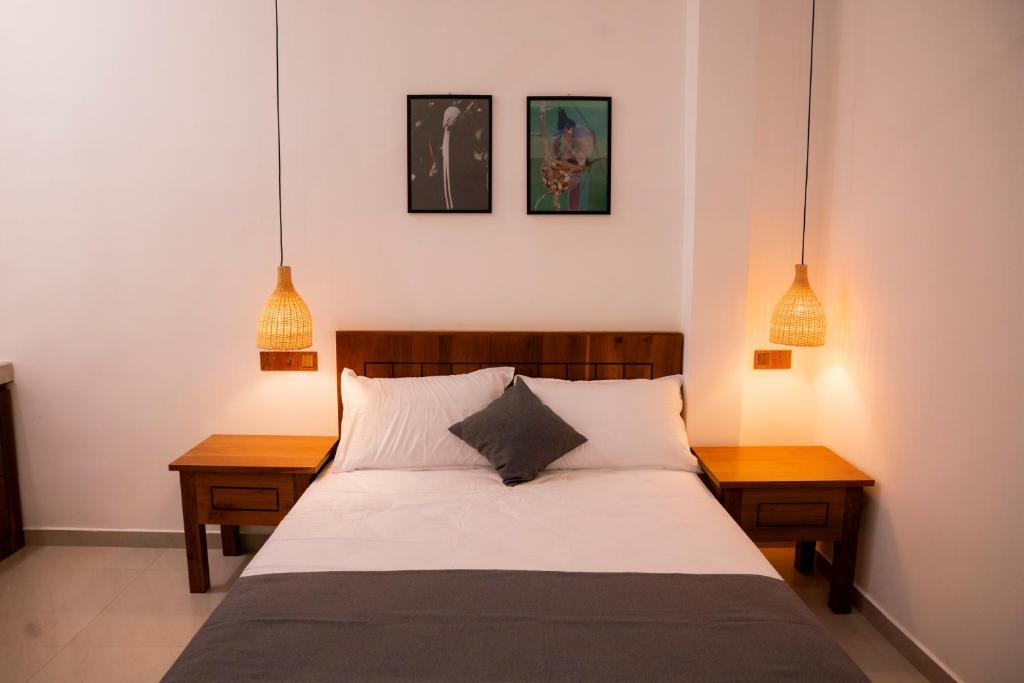 a bedroom with a bed with two tables and two pendant lights at Nest & Rest in Sri Jayewardenepura Kotte