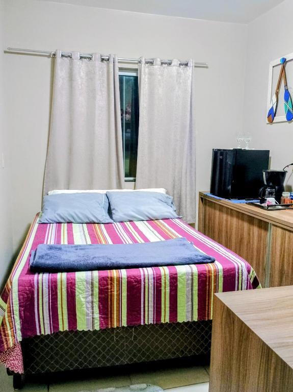 a bedroom with a bed with a striped blanket at Quarto em residência familiar in Navegantes