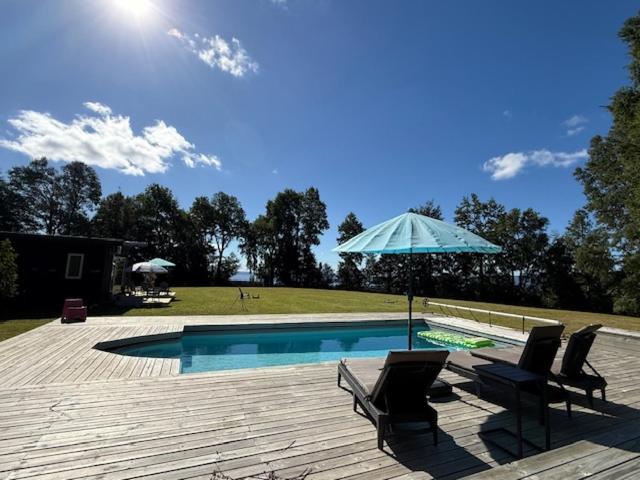 a swimming pool with two chairs and an umbrella at Rukachohan in Pucón
