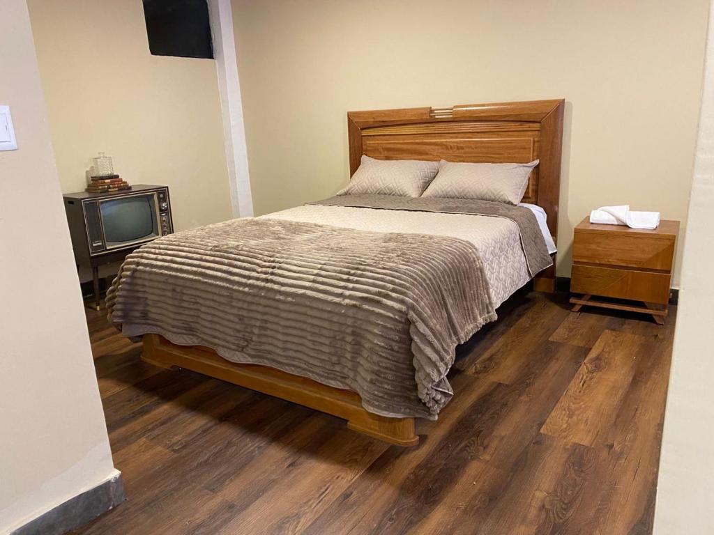 a bedroom with a bed and a tv on a wooden floor at Hotel Gavilu in Ambato