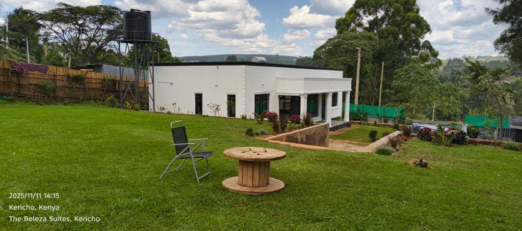a small white building with a table in the grass at The Beleza Suites in Kericho