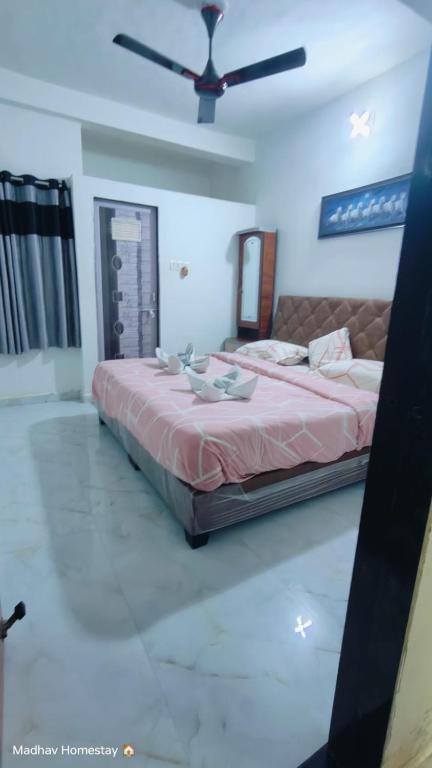 a bedroom with a large bed with a ceiling fan at UNiTY MADHAV HOMESTAY in Kevadia
