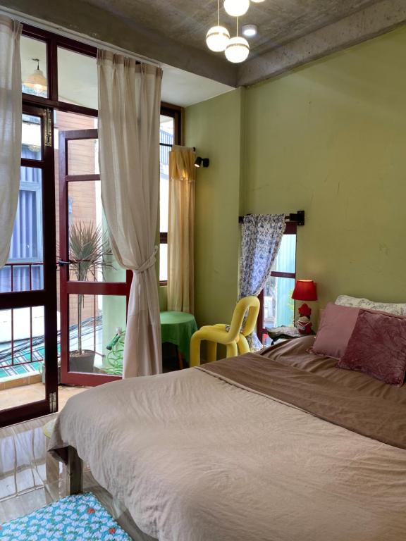 a bedroom with a large bed in a room with windows at Tiny bright house Autum space in Danang