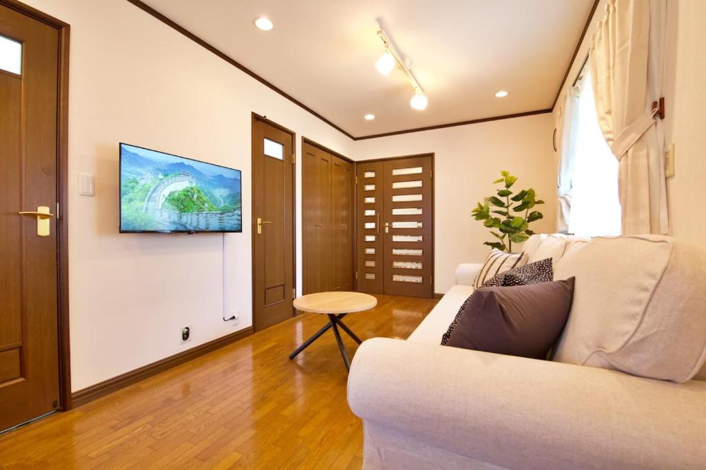a living room with a couch and a tv on a wall at Forest Inokashira in Mitaka