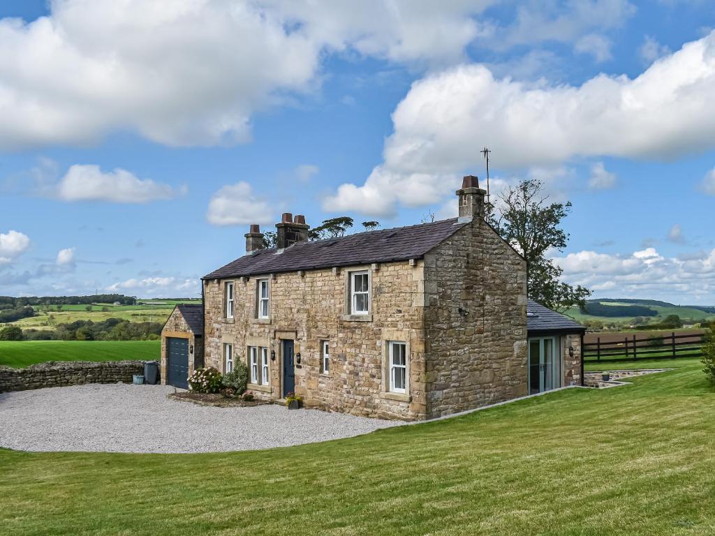 an old stone house with a gravel driveway at Swiss Cottage in Lancaster