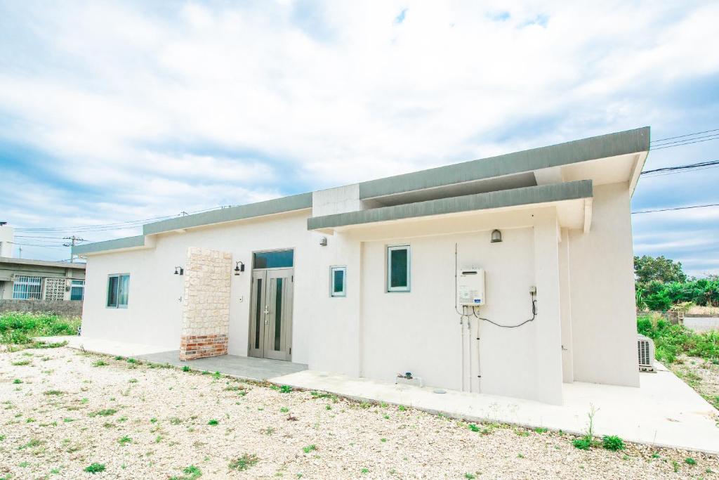 a small white building with a basketball hoop at キジムナー MIYAKO Hotel in Miyakojima