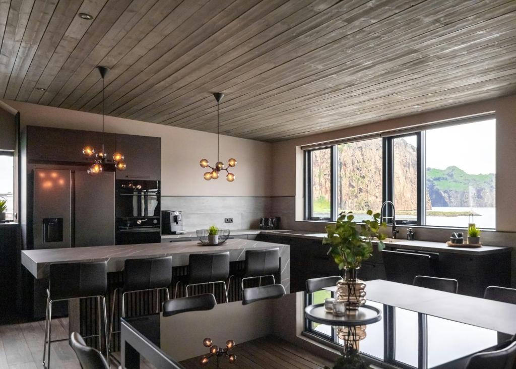 a kitchen with black chairs and a wooden ceiling at Pier Apartments in Vestmannaeyjar