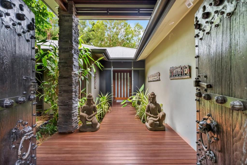 a home with a wooden walkway with statues on it at Belle Escapes Samaya in Palm Cove