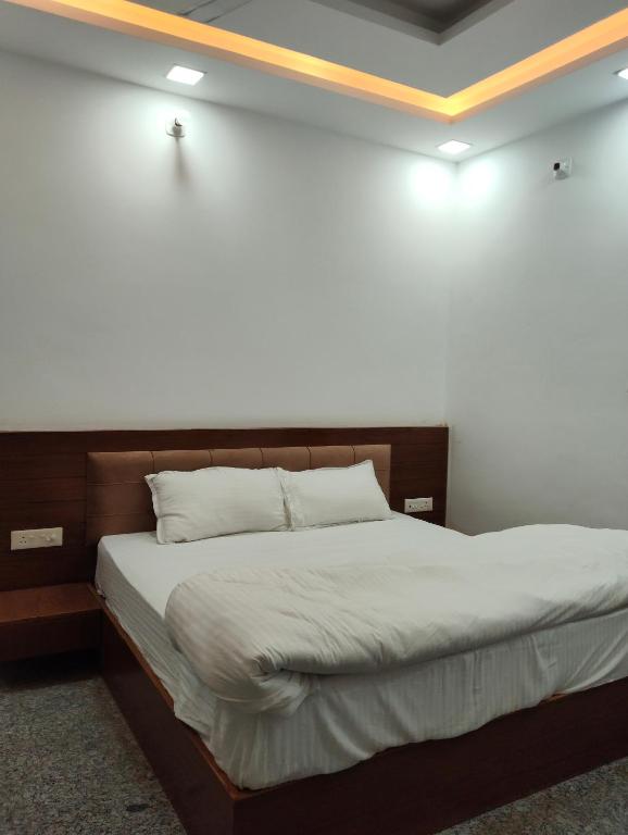 a bed in a room with a white wall at Prithvi hotel and restaurant in Mussoorie
