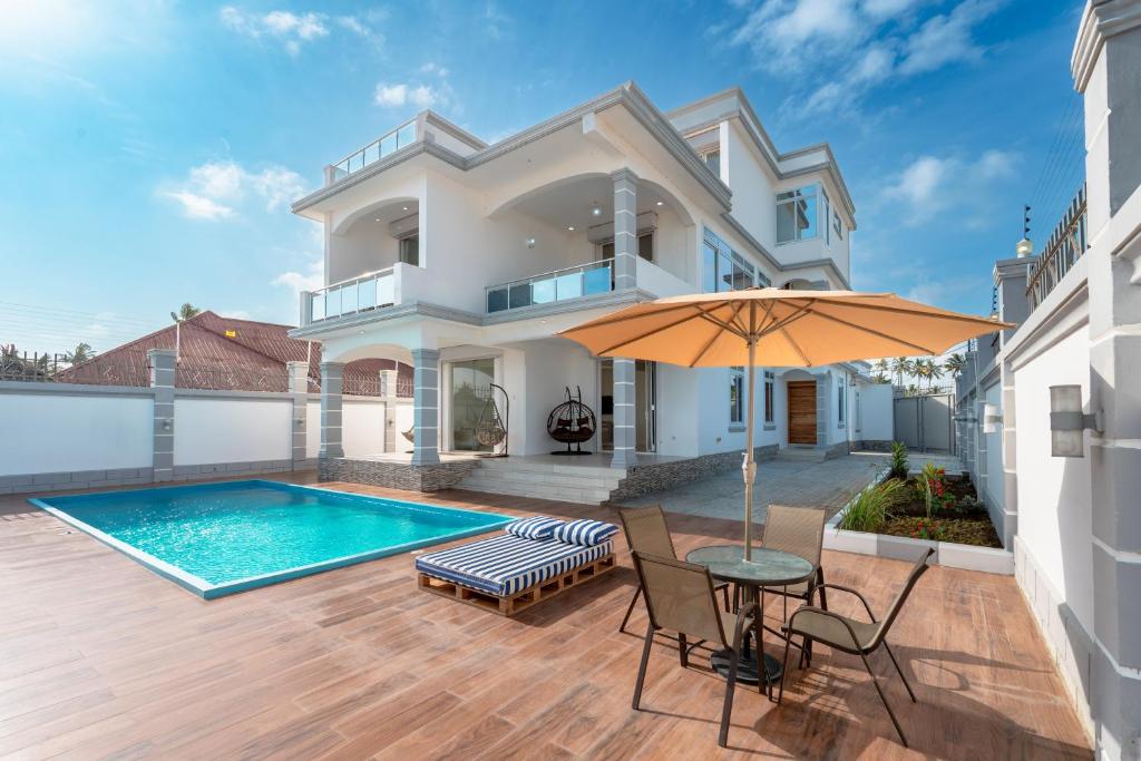 a house with a swimming pool and a table with an umbrella at Bahari Beach Front Villa in Mdudu Mkubwa
