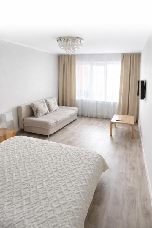 a white living room with a bed and a couch at Рахмет in Petropavlovsk