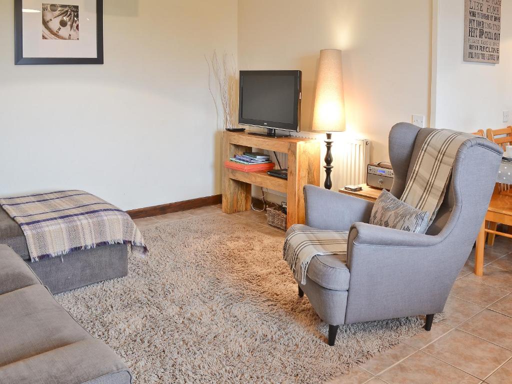 a living room with a couch and a chair and a television at The Buttery in Marros
