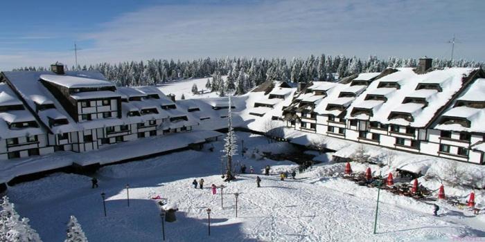 un edificio cubierto de nieve con gente en la nieve en Apartment Suncani Vrhovi, en Kopaonik