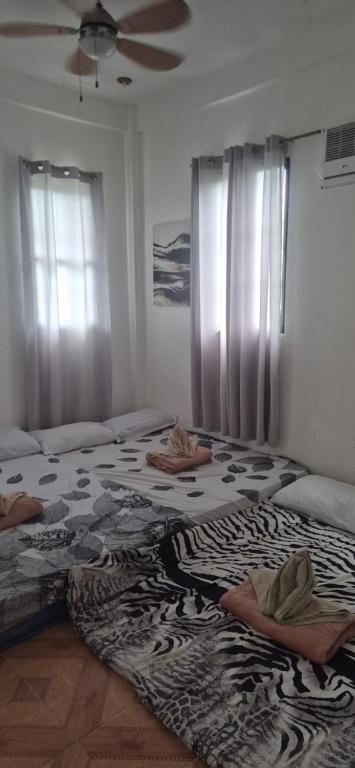 a bedroom with two beds and a fan and windows at Bohol Panglao Paradise Villa in Panglao Island