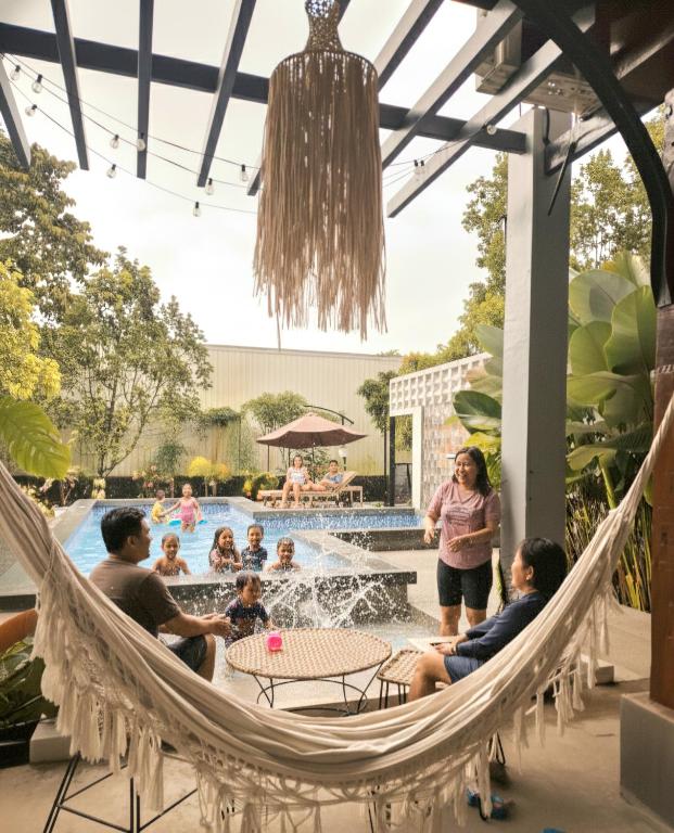 Eine Gruppe von Menschen sitzt in einer Hängematte an einem Pool. in der Unterkunft La Granja Farmstay Dipolog in Mutia