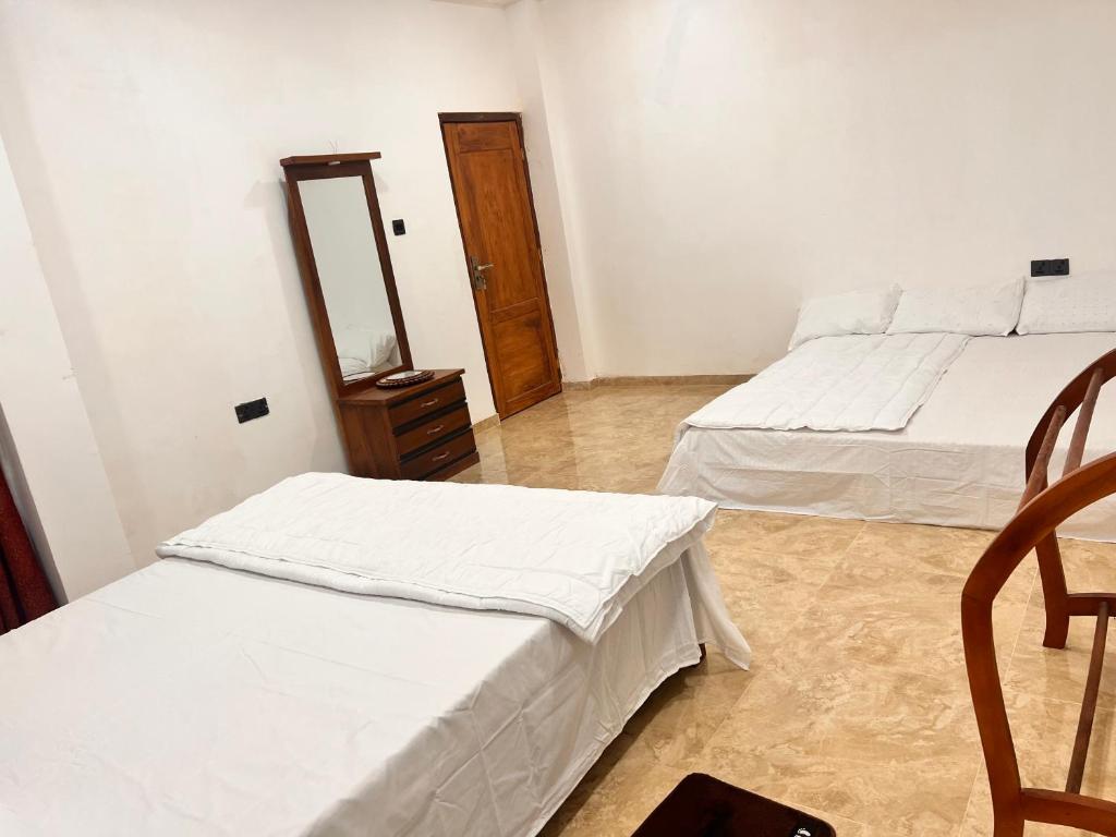 two beds in a room with two chairs and a mirror at River Side Guest House in Hatton