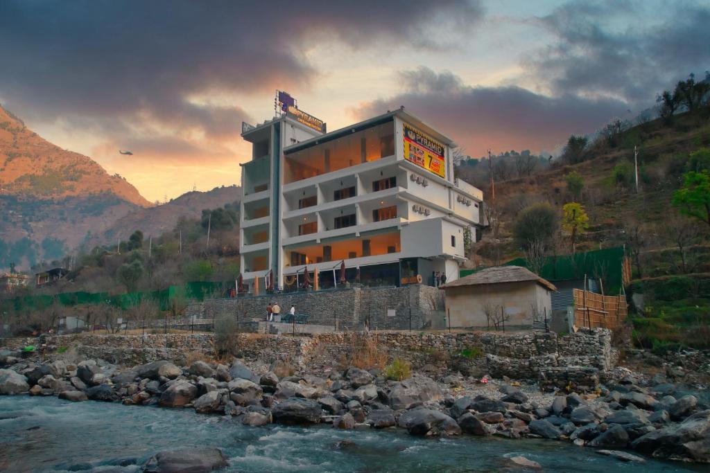 a hotel on a hill next to a river at Echor Palm Bliss Resort & Spa, Kasol in Kasol
