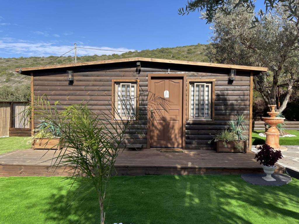 a small cabin with a wooden deck in a yard at השקט של כליל in Clil