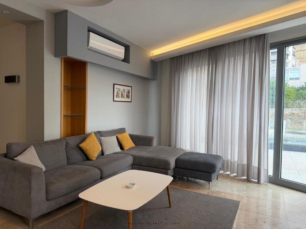a living room with a couch and a table at Maison by Grey Pearls Suites in Mīnāʼ al ‘Atīqah