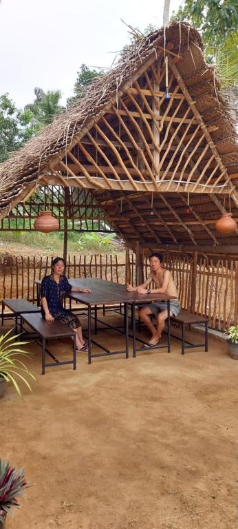 two people sitting at a picnic table under a roof at Mango Mango in Tangalle