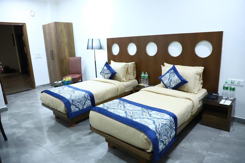 a hotel room with two beds with blue and white sheets at Nivasaah in Jāmb