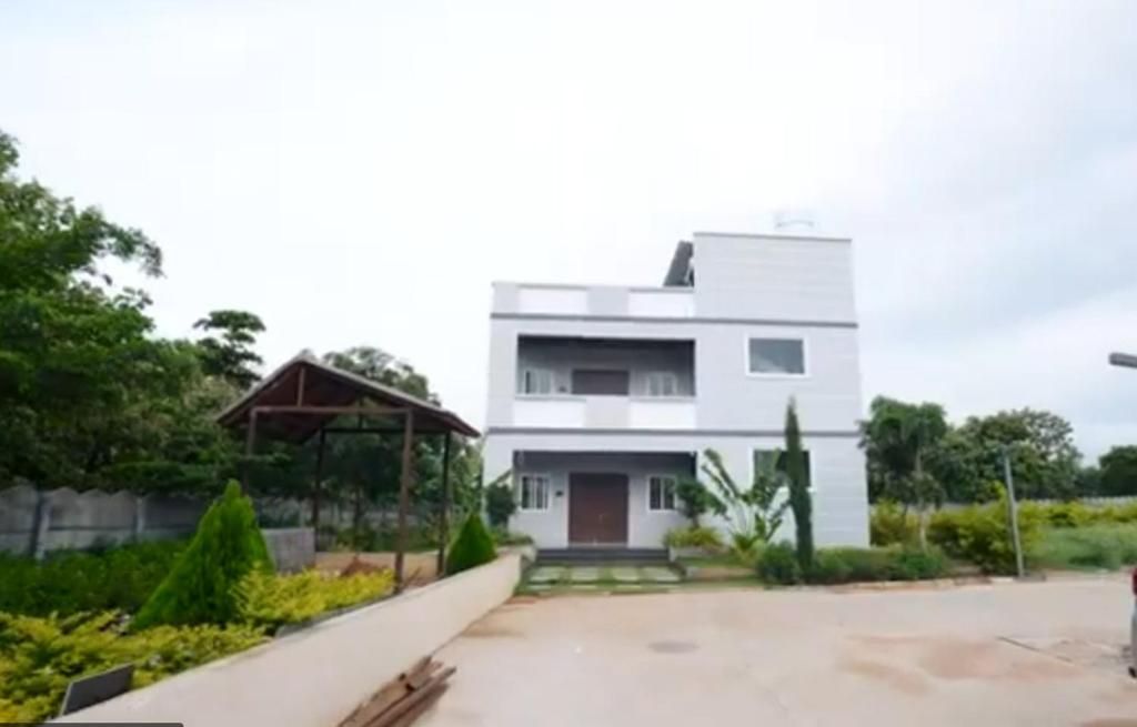 a white house with a driveway in front of it at Aacasa Living Resorts in Shamshabad