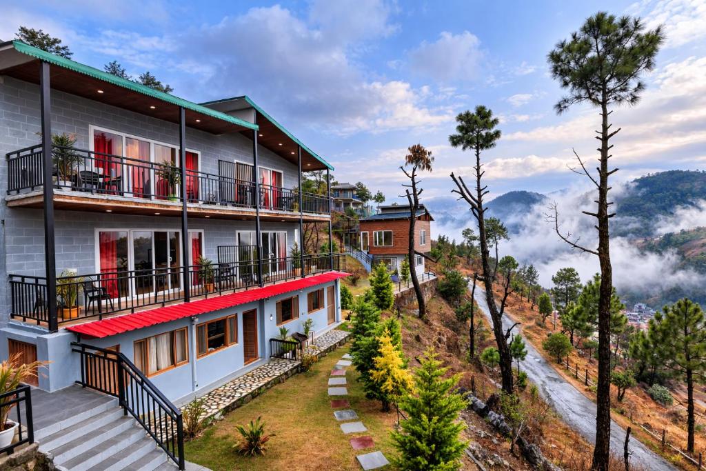 a house on the side of a hill with trees at Pine Country Resort in Mukteshwar