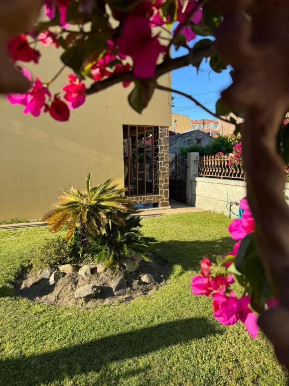 a house with pink flowers in front of a yard at Casa Regina in O Grove