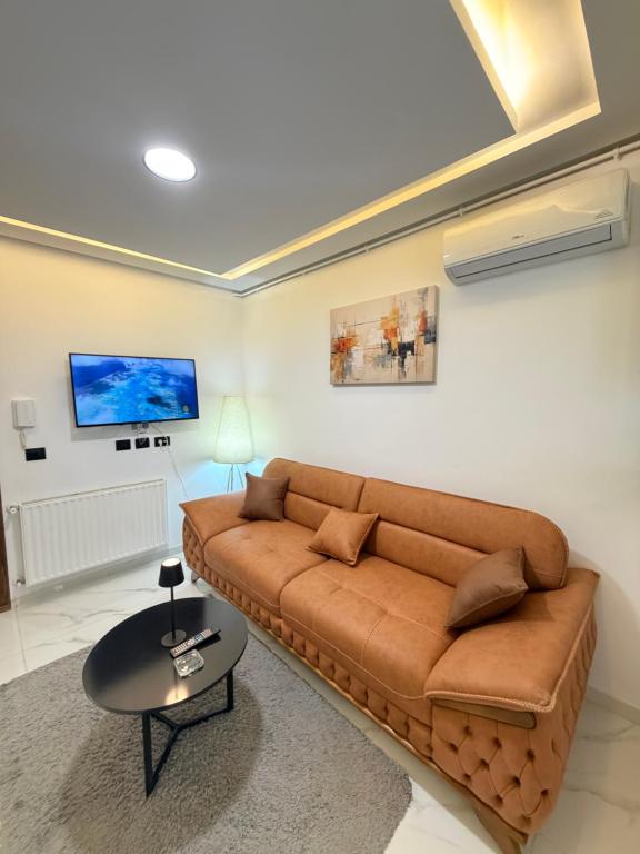 a living room with a brown couch and a table at Premium Suite - Ain zaghouen - proche aeroport - linge hotel in El Aouina Station