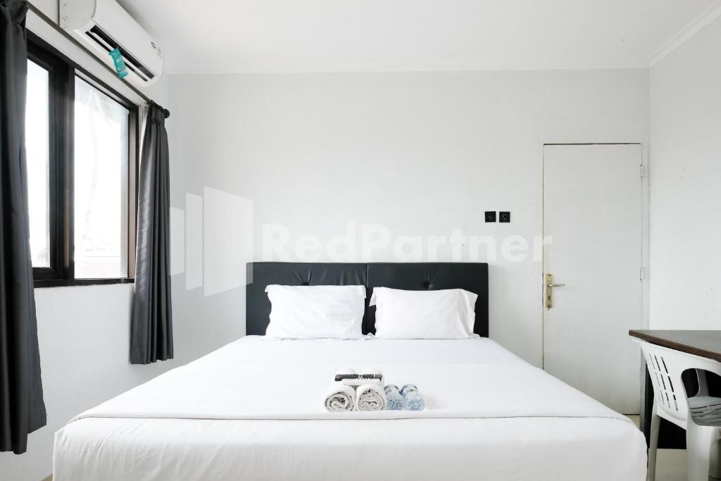 a bedroom with a white bed with two shoes on it at Aster Triplets Guest House JCM Mitra RedDoorz in Yogyakarta