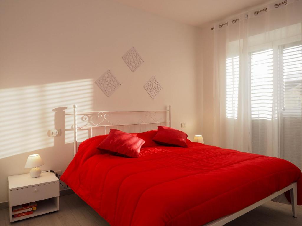 a red bed with red pillows in a white bedroom at Affittacamere 1888 in Pietrelcina