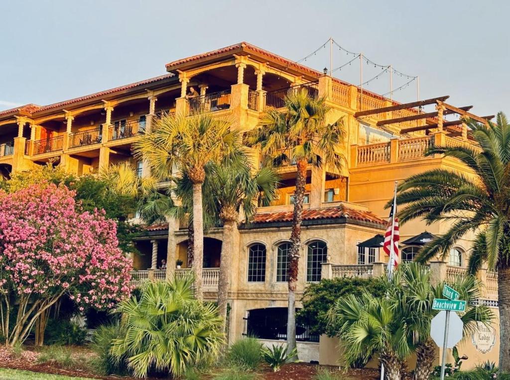 a large yellow building with palm trees in front of it at Ocean Lodge Resort in Saint Simons Island