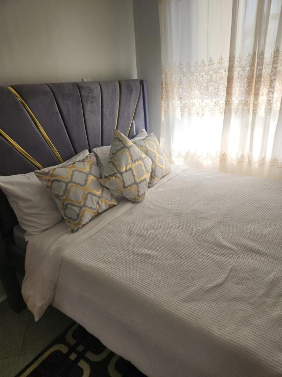 a bed with a headboard and pillows with a window at Happy Dany Stays in Kiahuria