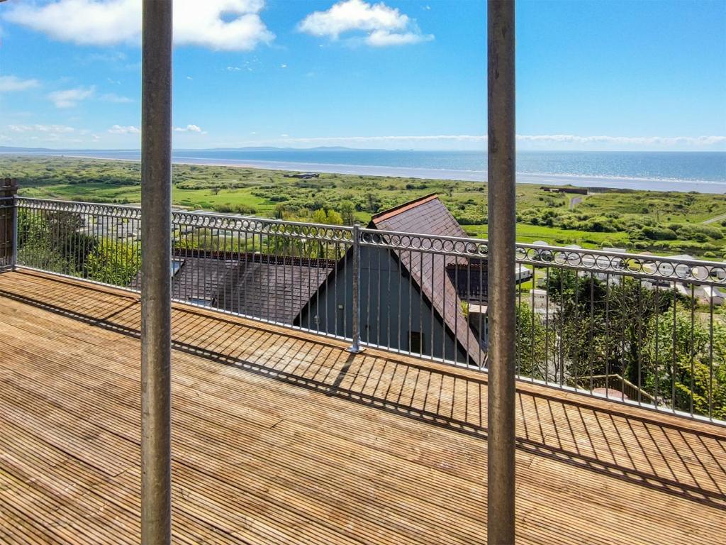 a balcony with a view of the ocean and a building at Pendine Beach Apartment in Pendine