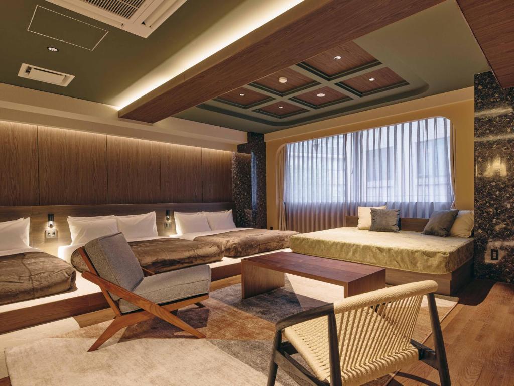 a bedroom with two beds and a chair and a table at illi Eme Tokyo-Toranomon in Tokyo