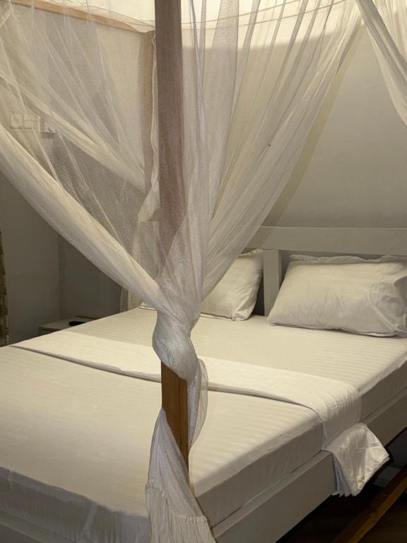 ein Bett mit weißem Moskitonetz in der Unterkunft Dindini in Kilindoni
