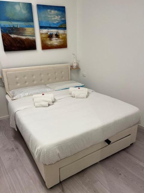 a white bed in a room with paintings on the wall at Comfort Room in Treviso
