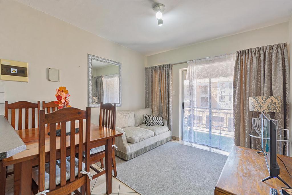a living room with a table and a dining room at Calmwood Stay in Midrand