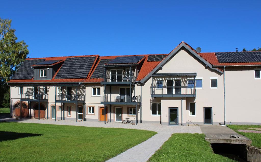 a large white building with solar panels on its roof at Glöckle Mühle, Ferienwohnungen und Camping mit Sauna in Herbolzheim