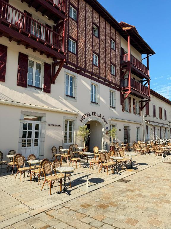 a group of tables and chairs in front of a building at Hôtel-Restaurant de La Paix in Saint-Palais