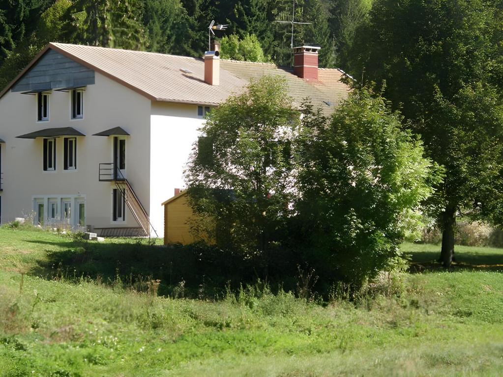 a white house with a tree in a field at Gîte Ancien Relais De Poste in Les Rousses