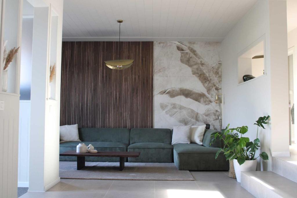 ein Wohnzimmer mit einer grünen Couch und einem Tisch in der Unterkunft Moderne woning met 3 kamers voor 7 personen met gratis parking in Haaltert