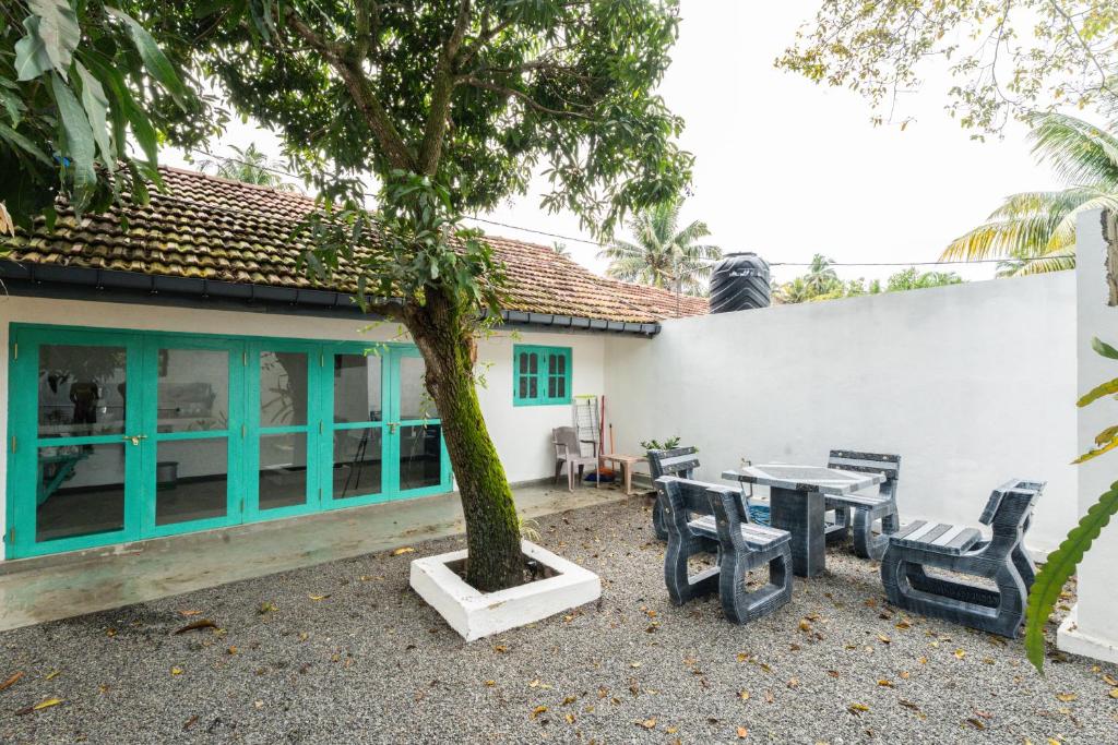 a building with a table and chairs and a tree at Villa Pigeon Paradise in Unawatuna