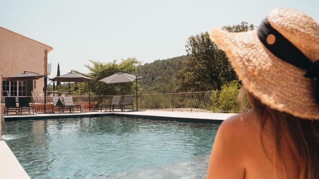 a woman wearing a straw hat standing next to a swimming pool at Domaine du PIAOU "chambres & table d'hôte" in Le Val