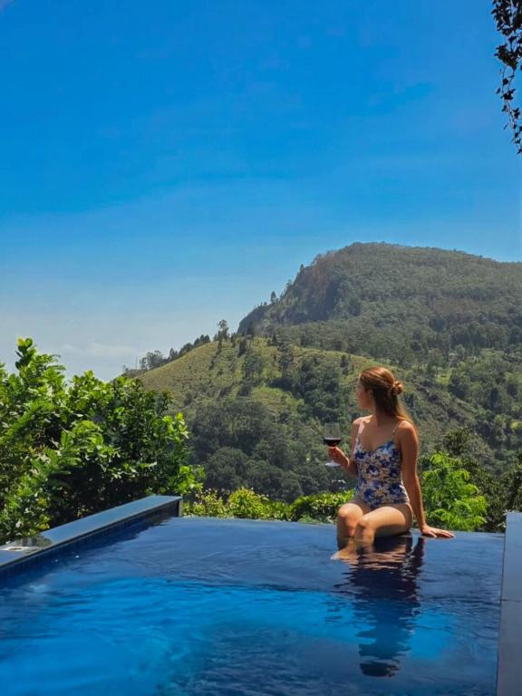a woman sitting on the edge of a swimming pool at Serenite Ella in Ella