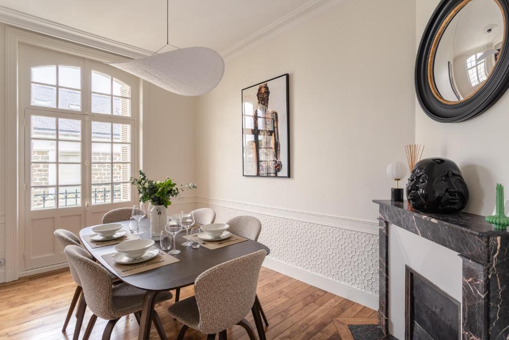 a dining room with a table and chairs and a fireplace at Ker Marlyne - Proche du Port in Dinard