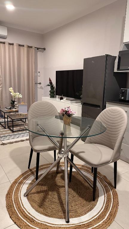 a dining room with a glass table and two chairs at The F402 Residence in Gaborone