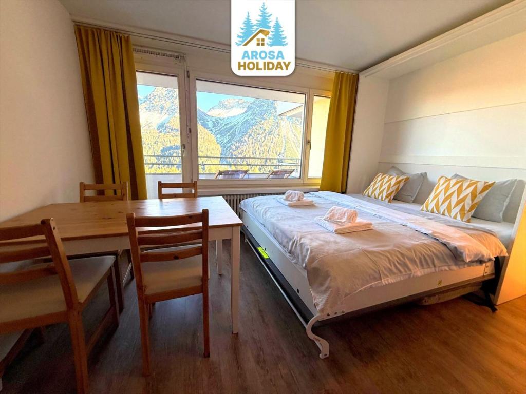 ein Schlafzimmer mit einem Bett, einem Schreibtisch und einem Tisch in der Unterkunft Fortuna 8 by Arosa Holiday in Arosa