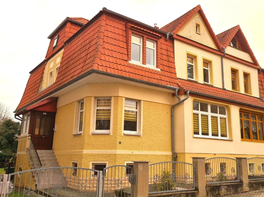a yellow and orange house with a red roof at Domizil NauNik in Naumburg