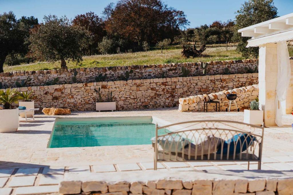 a swimming pool in front of a stone wall at Trullo del Benessere in Martina Franca